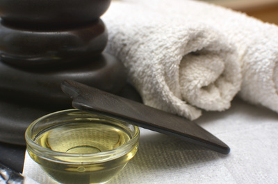 picture of gua sha tool, towels, and small bowl of oil.